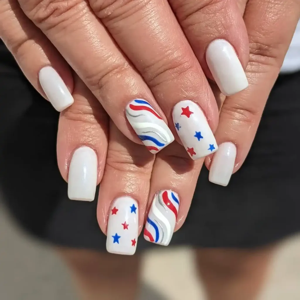 Long 4th of July nails with a white base, mini stars in red and blue, and curved lines for a subtle patriotic look